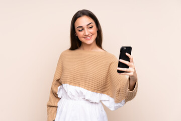 Young caucasian woman isolated on beige background making a selfie