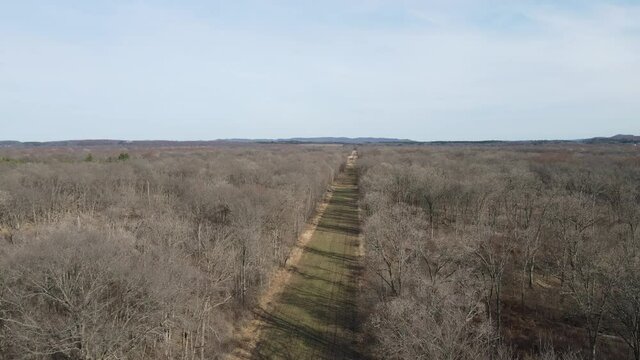 A beautiful aerial 4K shot of a dirt road in the Cranes Bend in Durand, Wisconsin along the Chippewa river - leafless forest
