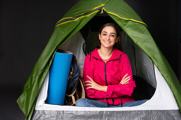 Young caucasian woman inside a camping green tent keeping the arms crossed in frontal position