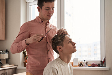 Man cutting hair of his boyfriend at home