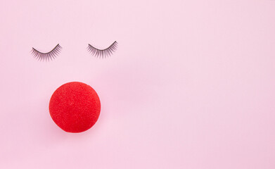 Top view of eyelashes and red clown nose isolated on pink background with copyspace