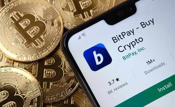 BitPay app seen on the smartphone screen placed on top bitcoin coins pile. Concept. Stafford, United Kingdom, April 12, 2021.