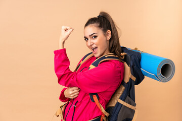 Obraz premium Young mountaineer girl with a big backpacker isolated on beige background making strong gesture