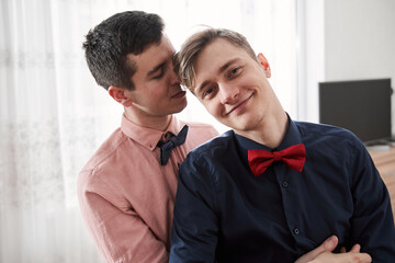 Man standing and looking at the camera with his boyfriend at home