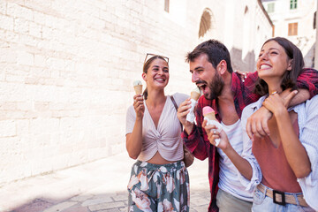 Happy group of friends walking in town and eating ice cream