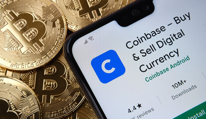 Coinbase app seen on the smartphone screen placed on top bitcoin coins pile. Concept. Stafford, United Kingdom, April 12, 2021.