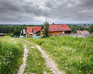 Village street in summer. Traditional wooden country houses. Village of Visim, Sverdlovsk region, Urals, Russia.