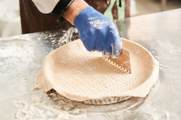 Man wearing protective gloves pierces the cake for speedy cooking on the table