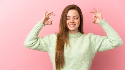 Teenager girl over isolated pink background in zen pose