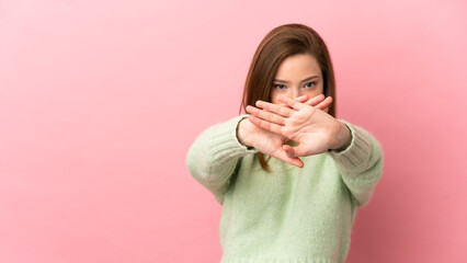 Teenager girl over isolated pink background making stop gesture with her hand to stop an act