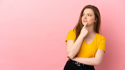 Teenager girl over isolated pink background having doubts while looking up