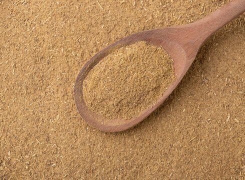 Top view, closeup of ground cumin on a wooden spoon