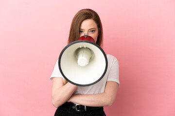 Teenager girl over isolated pink background shouting through a megaphone to announce something