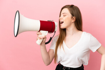 Teenager girl over isolated pink background shouting through a megaphone to announce something in...