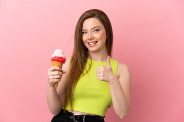 Teenager girl with a cornet ice cream over isolated pink background giving a thumbs up gesture