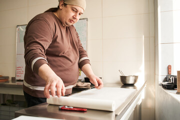 Baker putting paper at the table while preparing to the packing cakes