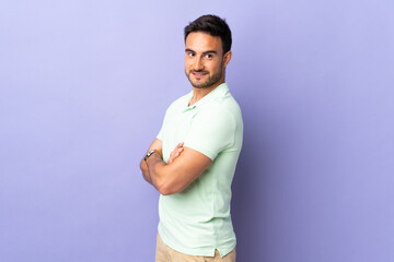 Young handsome man isolated on purple background looking to the side and smiling