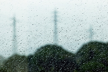 Glass with rain water drops and blurred shadows in the background.