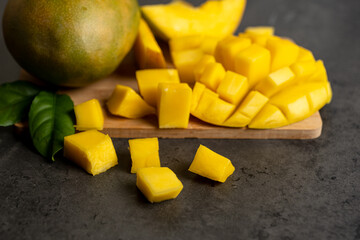 ripe mango cut into cubes on a dark gray background