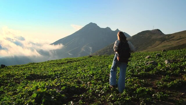 explore nature at summer vacation, young female backpacker is strolling at top of mountain
