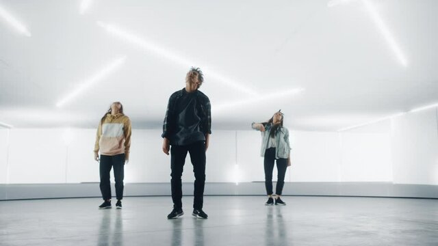 Diverse Group of Three Stylish Professional Dancers Performing a Hip Hop Dance Routine in Front of Big Led Wall Screen with 3D Garage Space Created for Virtual Production in Studio Environment