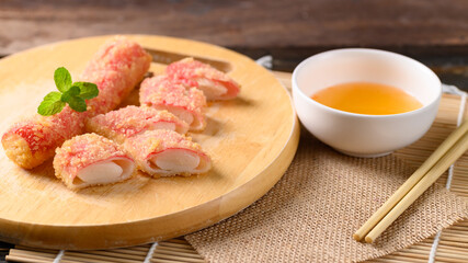 Deep fried crab sticks or surimi on wooden board eating with chili sauce