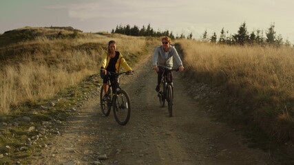 Couple riding sport bicycles on road. Happy cyclists exercising in mountains