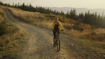 Focused woman riding sport bicycle on road. Cyclist exercising in mountains