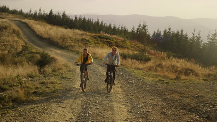Obraz premium Couple on bicycles riding on mountain road. Happy bicyclists training outdoor