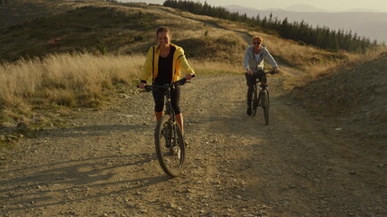 Couple cycling on sport bikes in mountains. Man and woman riding mountain bikes