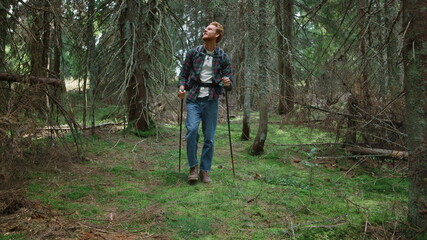Naklejka na ściany i meble Guy trekking in woods at summer. Male traveler hiking in fairytale forest