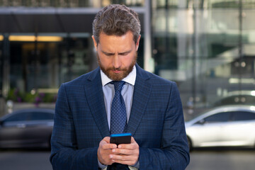 Business man texting message on smartphone near office.