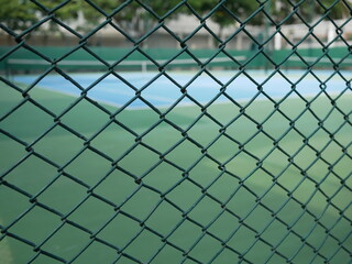 Fototapeta premium closeup of metal fence with blurred tennis court background. 