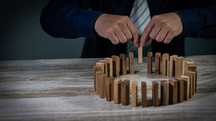 Businessmen grasp the circular wood blocks fall into planning and strategies that are vulnerable to...