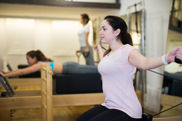 Woman exercising torson rotation at gym using pilates reformer beds