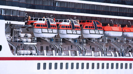 Orange and white life boats stored on the side of a cruise ship