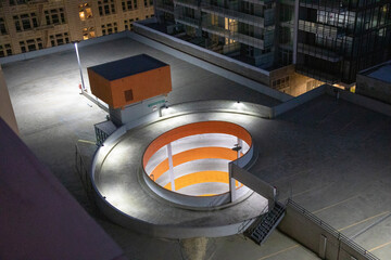Night image of an empty colorful parking lot in the middle of a building complex rooftop © Jill Greer