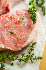 Raw pork meat with thyme and spices on the rustic background. Selective focus. Shallow depth of field.