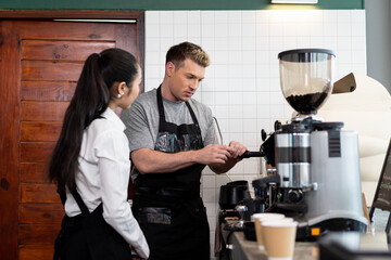Barista cafe  wearing apron and prepare coffee grinder pour at coffee shop with happy and smiling. Worker making coffee on steam espresso coffee machine
