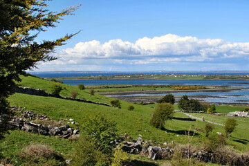 Horizontal shot of a beautiful landscape from the hill to green ground, blue sky and lakes