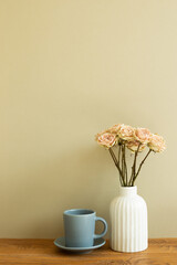 Coffee cup with dry rose flowers on wooden table. khaki beige background