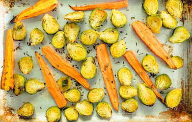 Grilled brussels sprouts and carrots with thyme herbs on the pan. Selective focus.