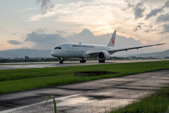 雨上がりの夕暮れ、雨で濡れた誘導路をタキシングする日本航空の旅客機　伊丹空港