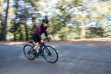 Mujer ciclista profesional a toda velocidad en una carretera en medio del bosque. Concepto de triatlón