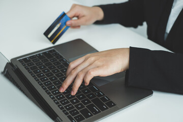 The businesswomen's hand is holding a credit card and using a laptop for online shopping and internet payment