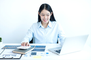 Asian female accountant sits at their desks and calculates financial graphs showing results about their investments, plan a successful business growth process