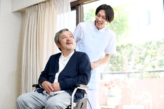 車椅子を押す男性介護士と笑顔のシニア男性
