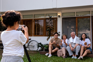 Happy Asian multi-generation family spending time together at home. Parents and grandparents with cute baby girl taking a photo together in front of home. Family relax and having fun weekend activity.