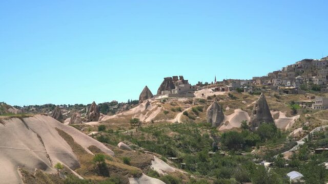 Uchisar hill and stone cave house architecture on the edge of fairy chimneys in Cappadocia.Limestone hoodoos and sedimentary fairy chimney rocks in an arid drainage basin valley.Anatolia Nevsehir 4K