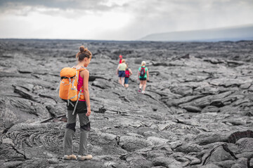 Hiking group of hikers walking on Hawaii volcano lava field hike adventure happy woman with backpack in Big Island, Hawaii. Tourists walking on guided tour trail outdoor USA summer travel vacation. - obrazy, fototapety, plakaty